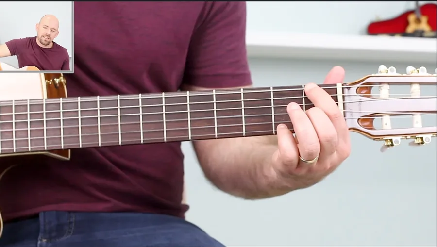 Aula com a mão em primeiro plano no braço do violão